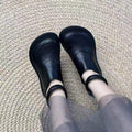 Black leather shoe with cross-laced wrap closure for comfortable daily walking