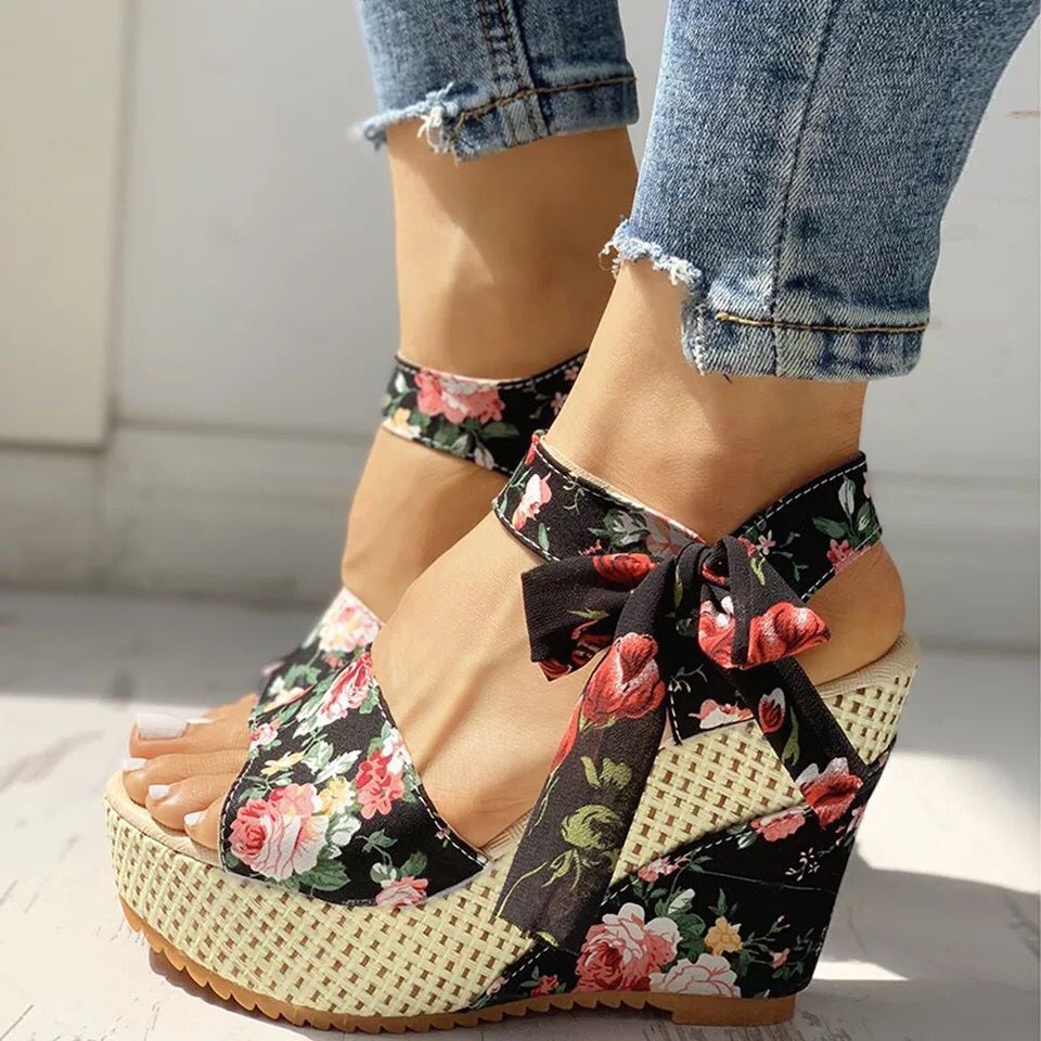Gorgeous pair of espadrilles with satin ribbons and floral embroidery on sun-warmed tile