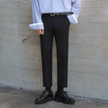 Tall male model wearing slim-fitting cotton suit pants with low-rise fit and expensive belt buckle, styled casually