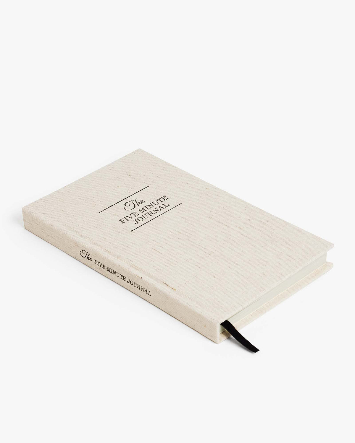 The Five Minute Journal with textured linen cover and lay-flat binding open on a wooden table