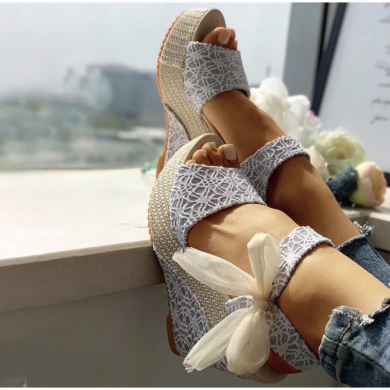 Gorgeous pair of espadrilles with cross-strap, padded footbed, and floral ribbon details on sunlit tile floor