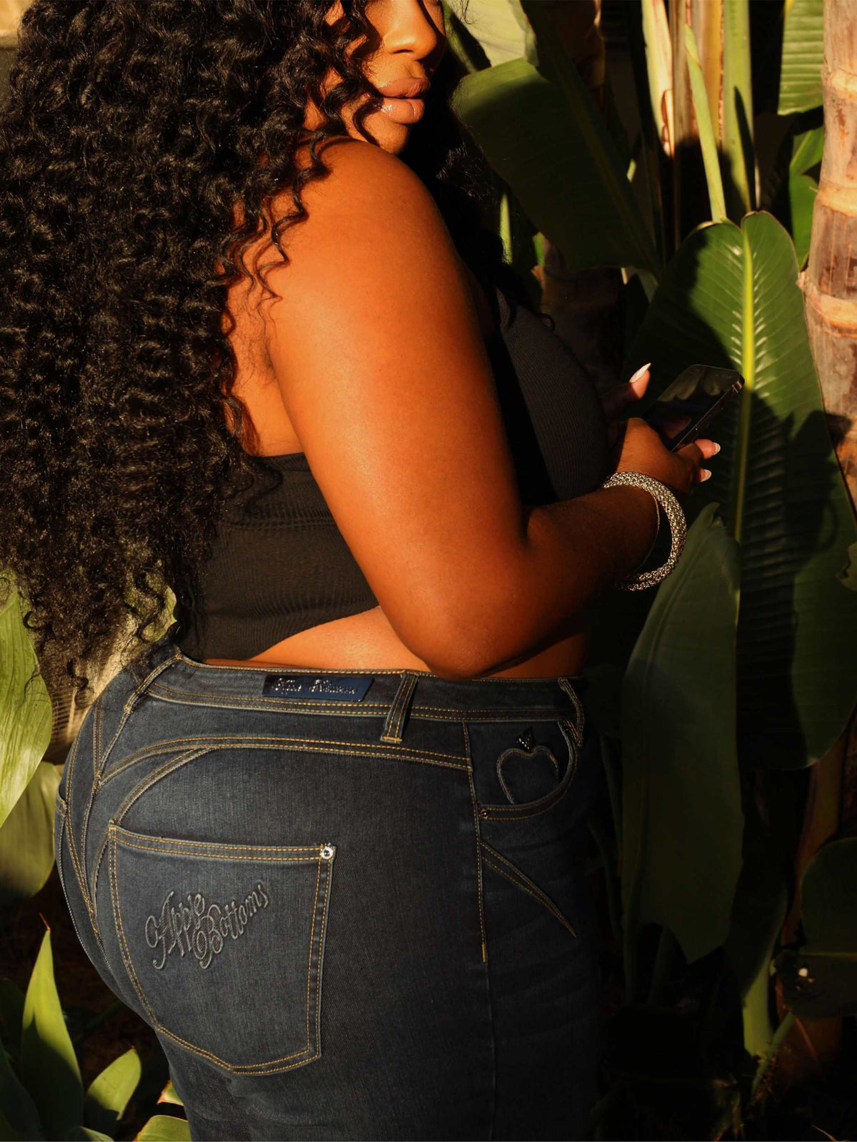 Close-up of Apple Bottoms brand thong stitched on denim jeans with detailed posterior shaping