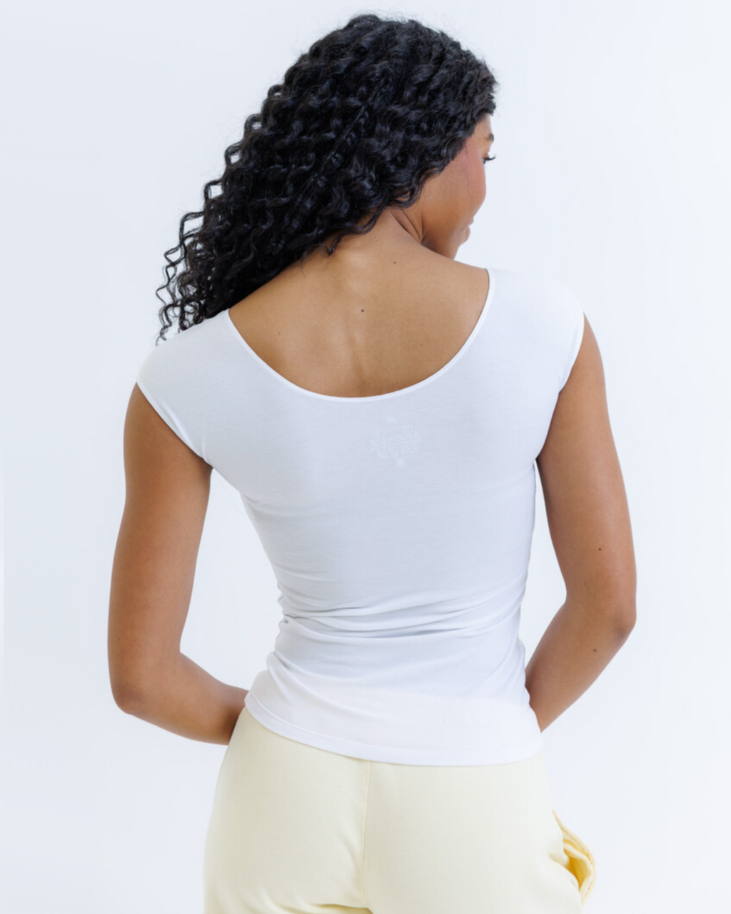White essential tee with a scoop neck and cap sleeves, breathable cotton-modal blend, fitted silhouette.