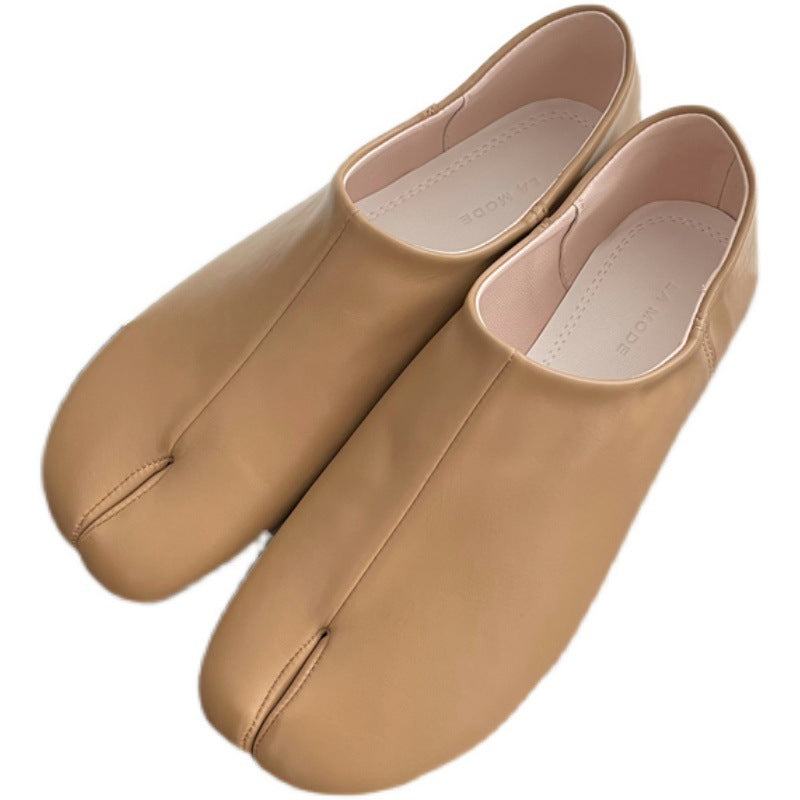 Black tabi shoe flats with split-toe design and flexible microfiber upper on hardwood floor