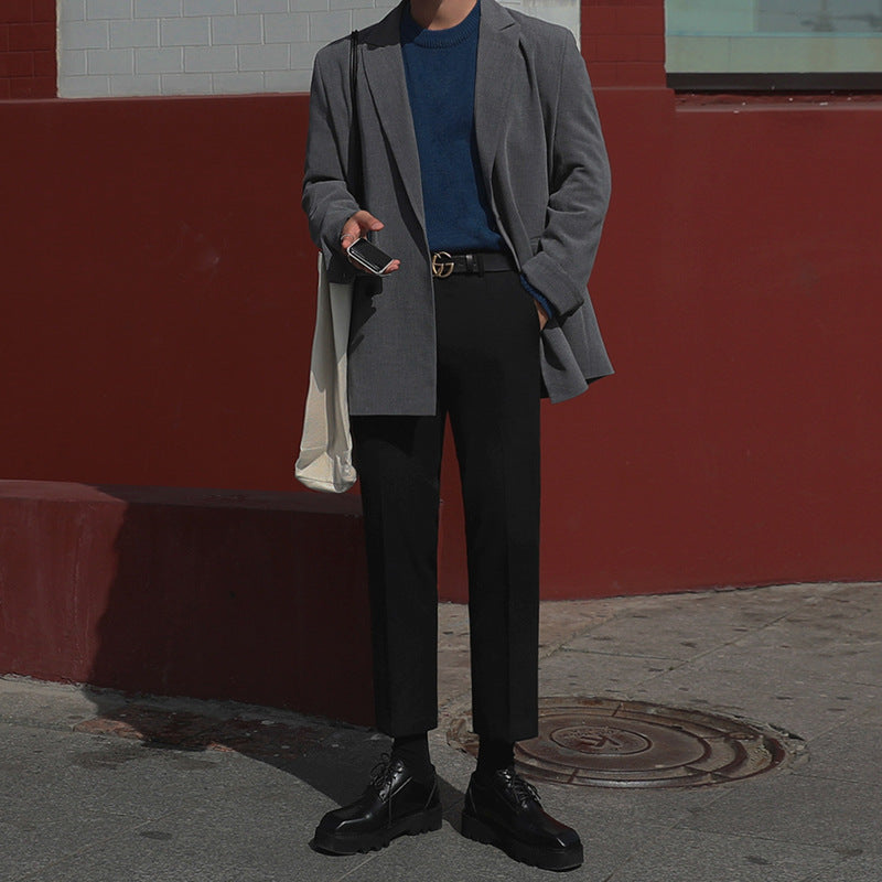 Tall male model wearing slim-fitting low rise suit pants with expensive belt buckle, casual pose