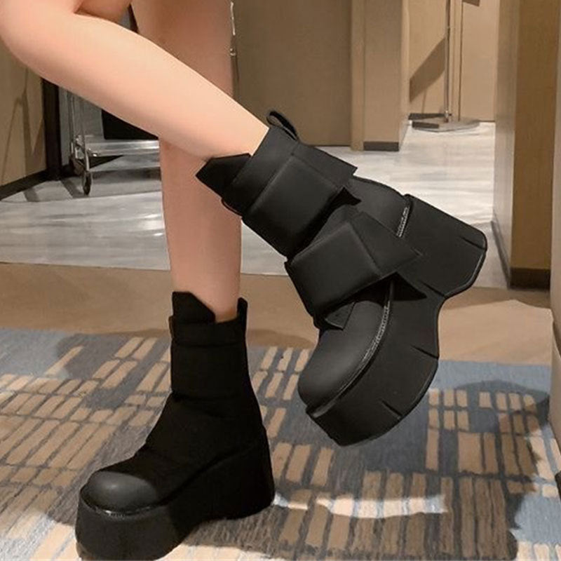 Black mid-calf platform boots with rounded toe and velcro closure styled with wide-leg pants