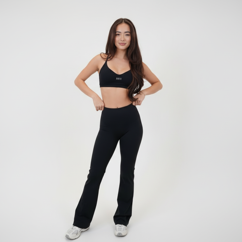 I Live in Luxury Flare Pant in black high-rise nylon blend with a soft flare hem worn with a black sports bra and white sneakers