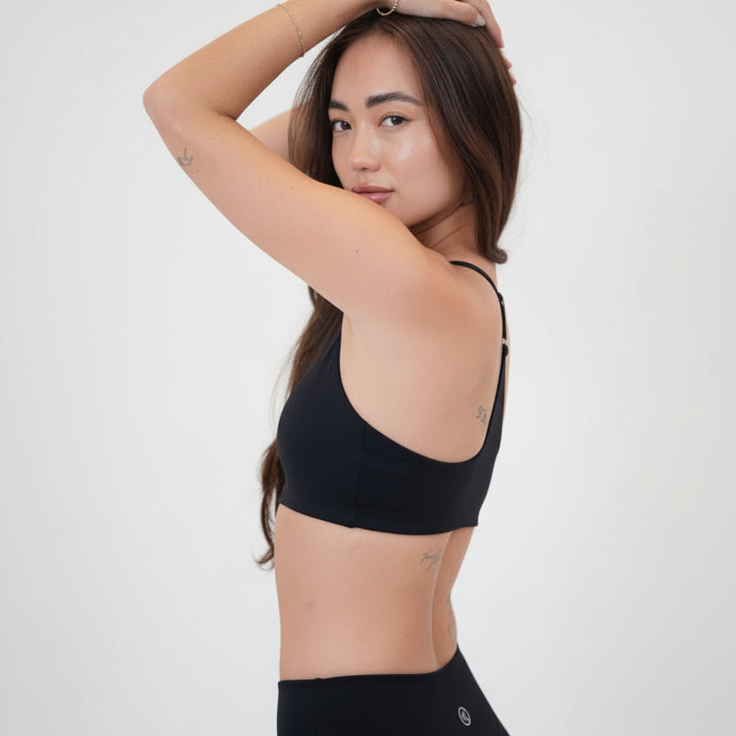 Luxury Black Sports Bra in smooth nylon-spandex blend with slim straps and scoop neckline shown on model from side