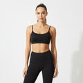 Luxury Black Sports Bra with slim straps and scoop neckline in smooth nylon-spandex blend worn by woman posing with arms raised