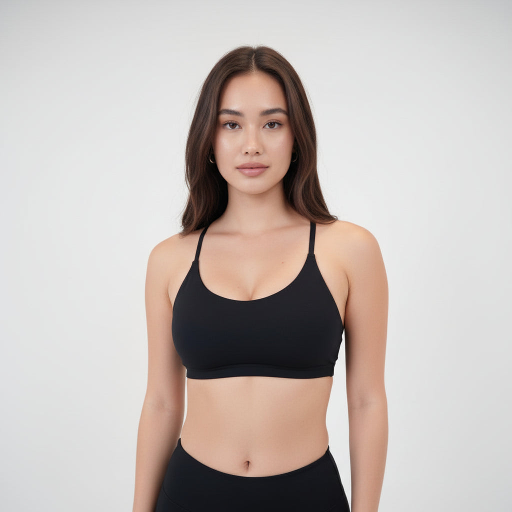 Luxury Black Sports Bra with slim straps and racerback design on model wearing black leggings, sleek nylon-spandex material