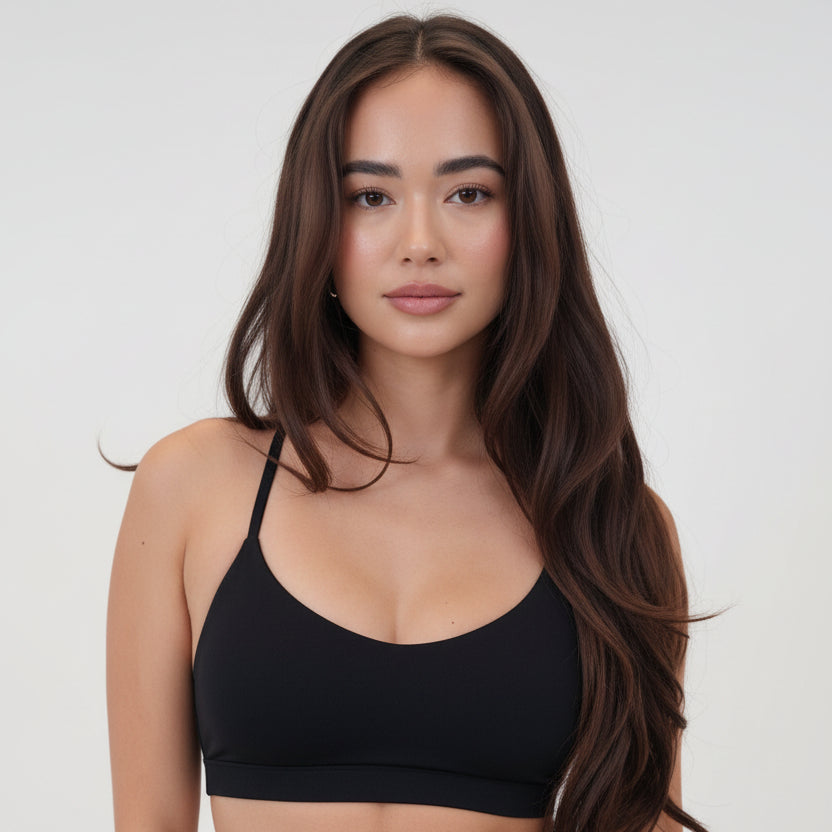 Luxury Black Sports Bra with slim straps and scoop neckline worn with matching black pants by a woman